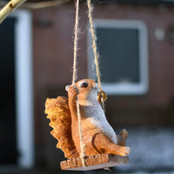 Tuinbeeldje van een eekhoorn op een schommel.
