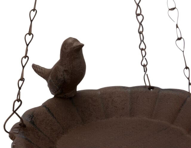 Gietijzeren vogeltje op de rand van een voederschaal voor vogels.